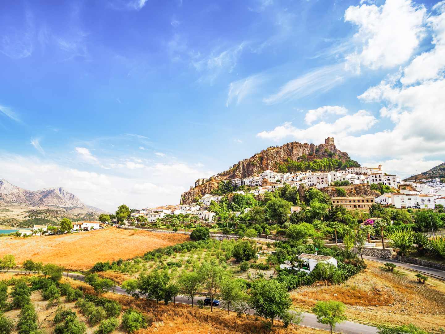 Zahara de la Sierra mit weißem Dorf und Burgfelsen in der Sierra de Cádiz unter blauem Himmel 