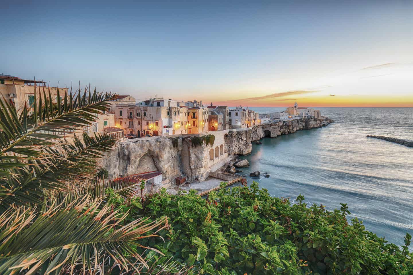 Apulien Urlaub mit DERTOUR. Die apulische Stadt Vieste auf einer Halbinsel im Meer bei Sonnenuntergang