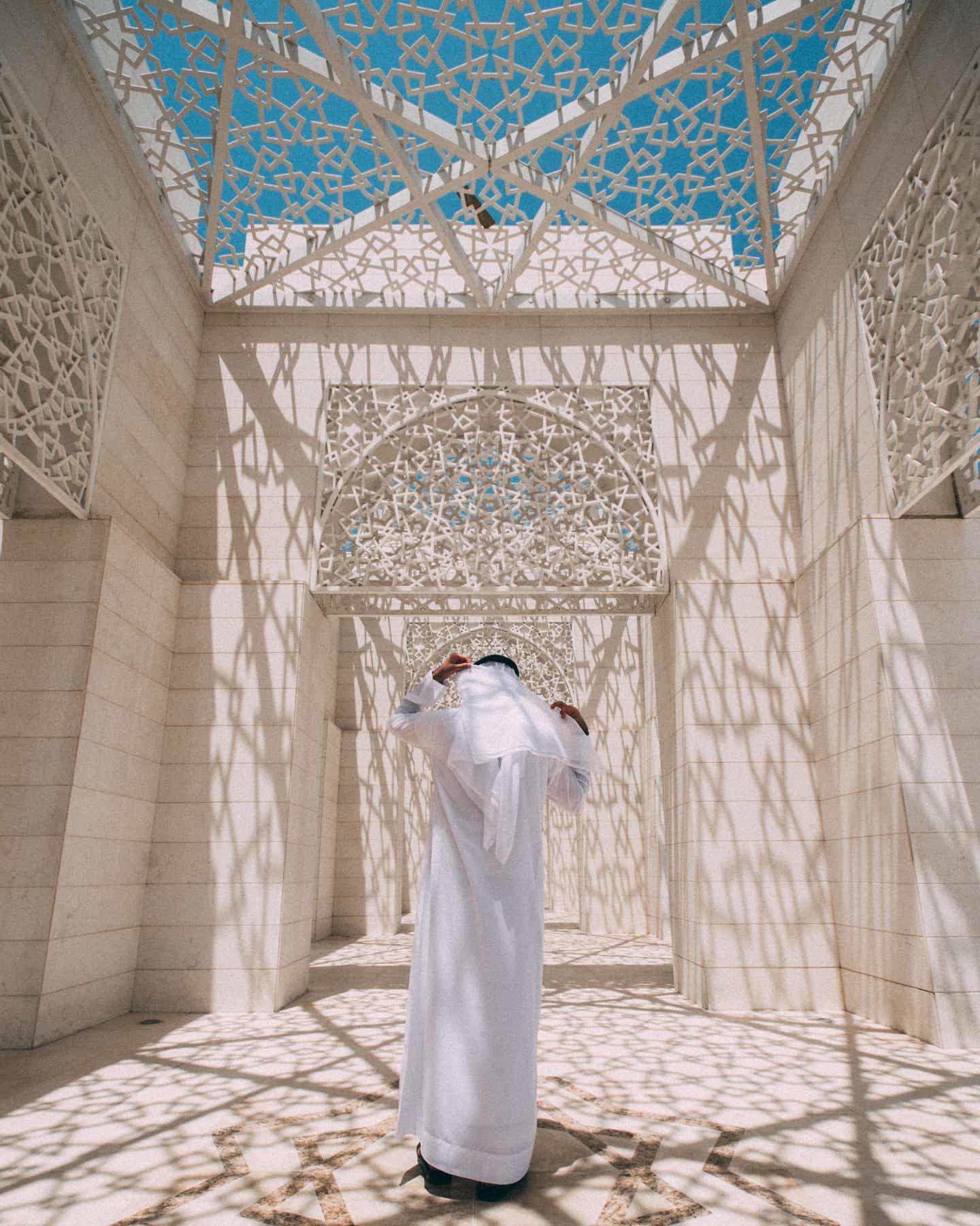 Mann steht im Gang von Moschee, die Decke wirft Schatten