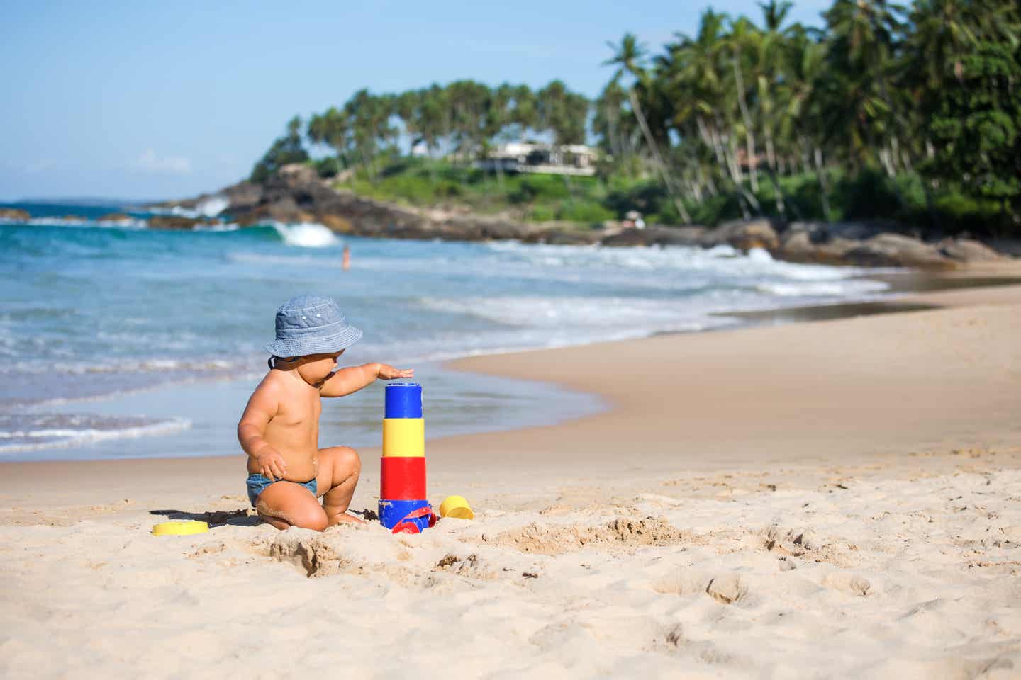 Kleinkind spielt mit Spielzeug am Strand