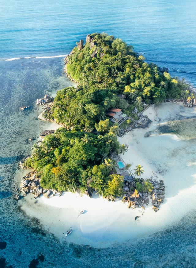 Schönste Inseln weltweit Blick auf das Constance Ephelia Resort auf den Seychellen, das auf einer kleinen grünen Insel auf einem Korallenriff liegt