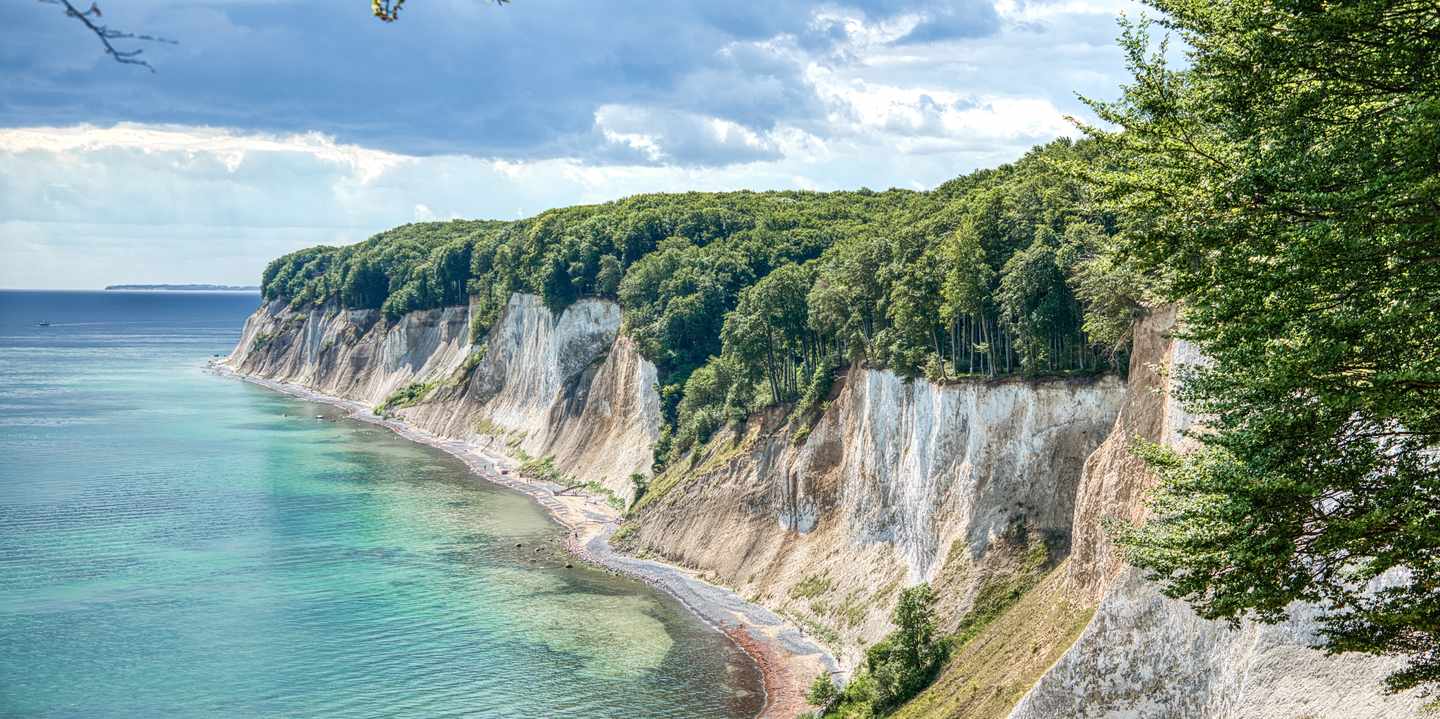 Weiße Kreidefelsen auf Rügen mit dichtem Buchenwald und türkisfarbenem Wasser der Ostsee