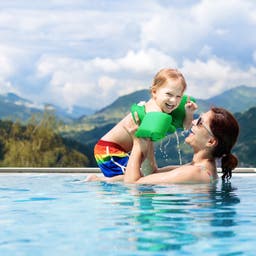 familienurlaub-mutter-und-kind-in-einem-pool-vor-bergkulisse-g-969118102.jpg