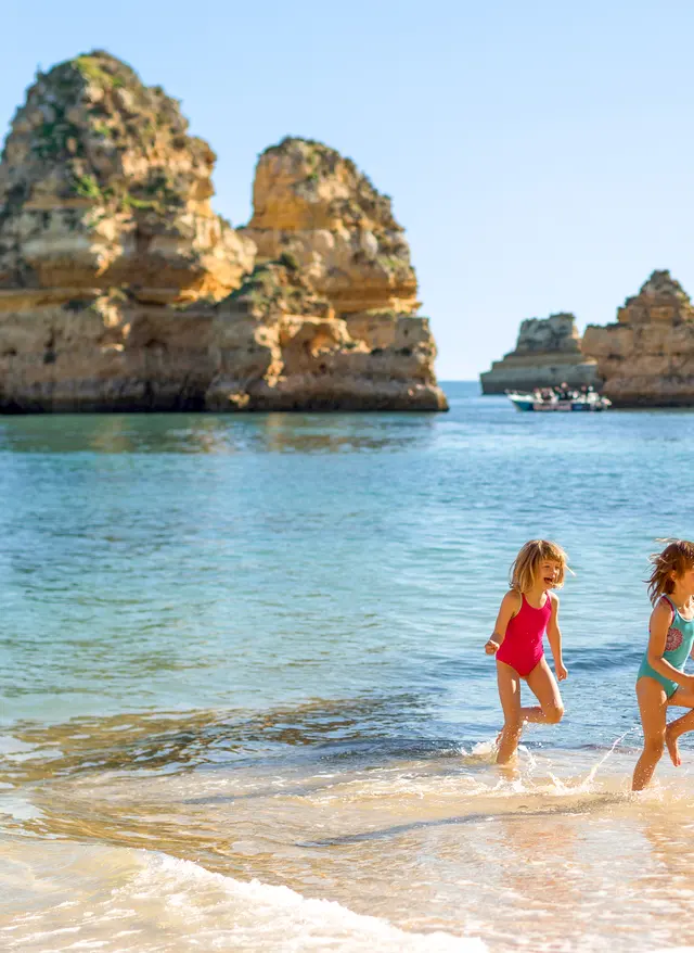 Familienurlaub Portugal Familienurlaub Portugal – Familie mit Kindern am goldenen Sandstrand der Algarve mit typischen Felsformationen