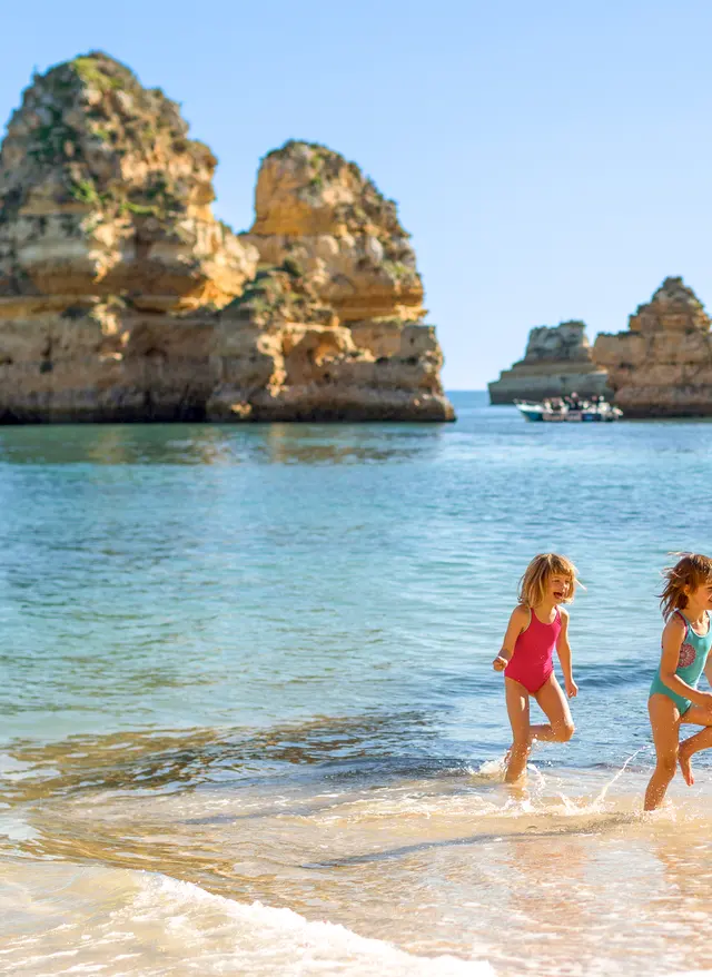 Familienurlaub Portugal Familienurlaub Portugal – Familie mit Kindern am goldenen Sandstrand der Algarve mit typischen Felsformationen