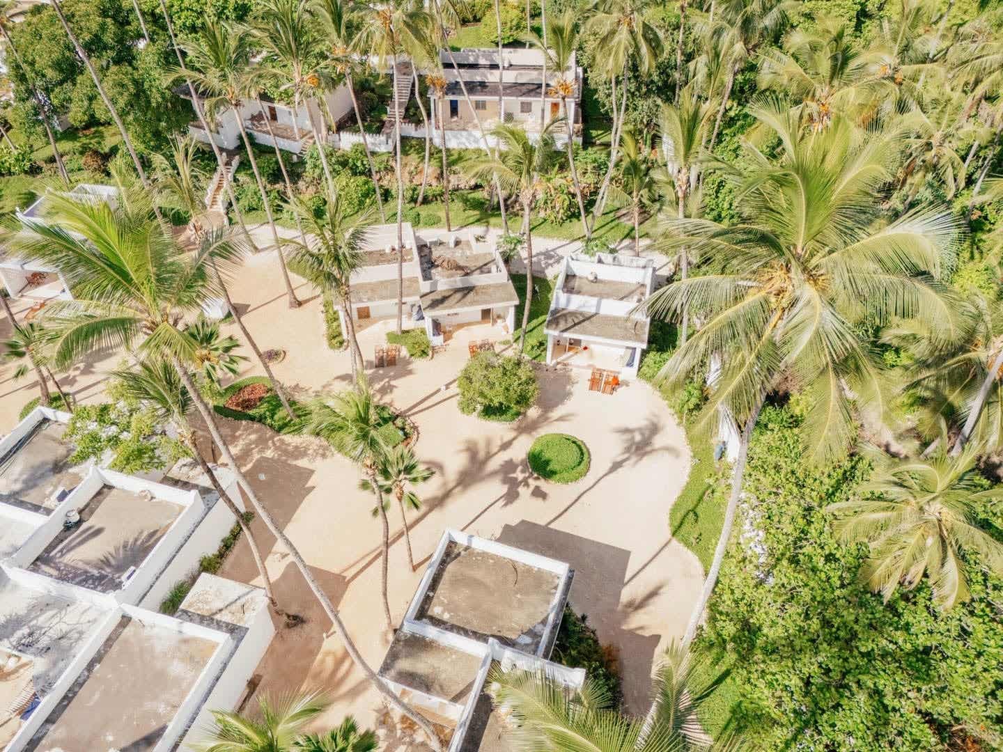 Bungalows unter Palmen im ananea Diamonds Mapenzi in Kiwengwa Luftaufnahme der Bungalows im ananea Diamonds Mapenzi in Kiwengwa, Sansibar – umgeben von hohen Palmen, tropischem Grün und sandigen Wegen