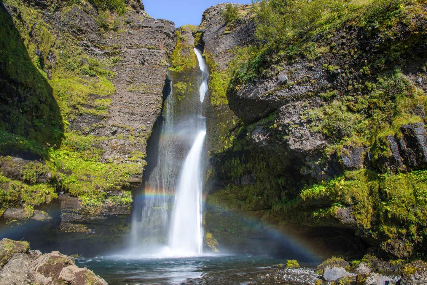 Idyllisch plätschert das Wasser des Gluggafoss bei Sonnenschein die bemoosten Felsen herab.
