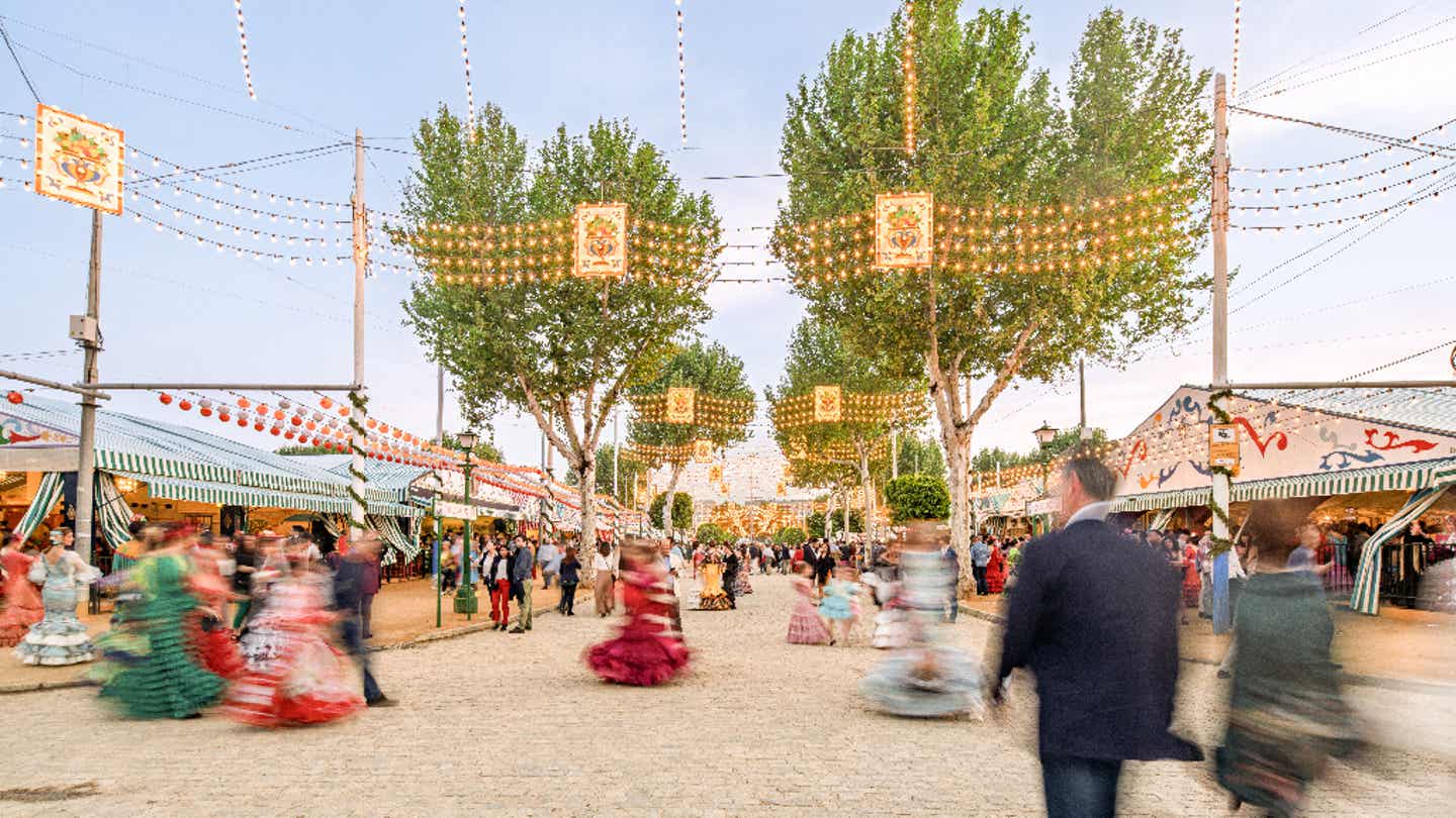 Feria de Abril in Sevilla mit festlich geschmückten Straßen, Lichterketten und tanzenden Menschen 