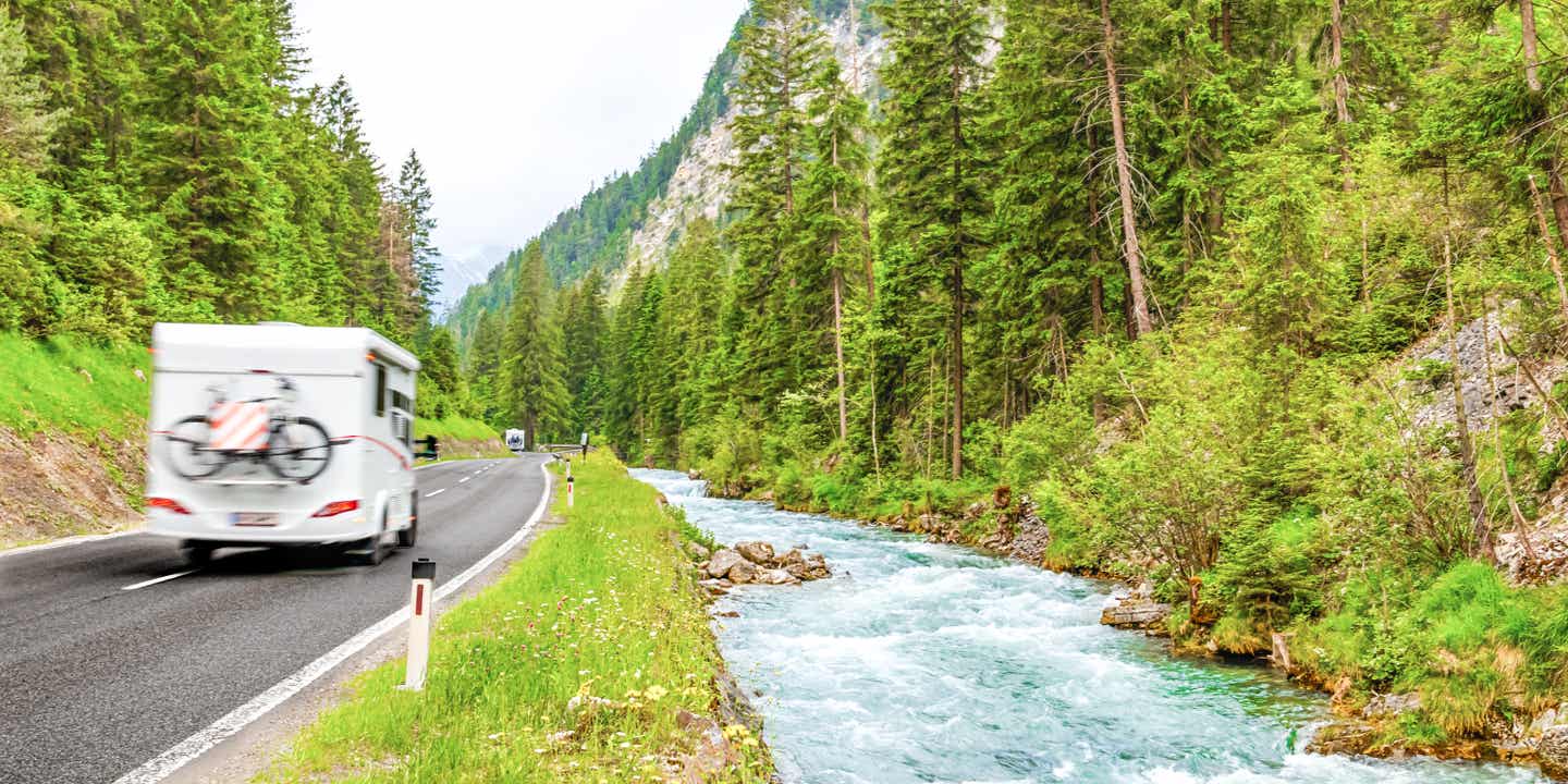 Ein Wohnmobil fährt auf einm Roadtrip durch Deutschland an einem rauschenden Fluss vorbei
