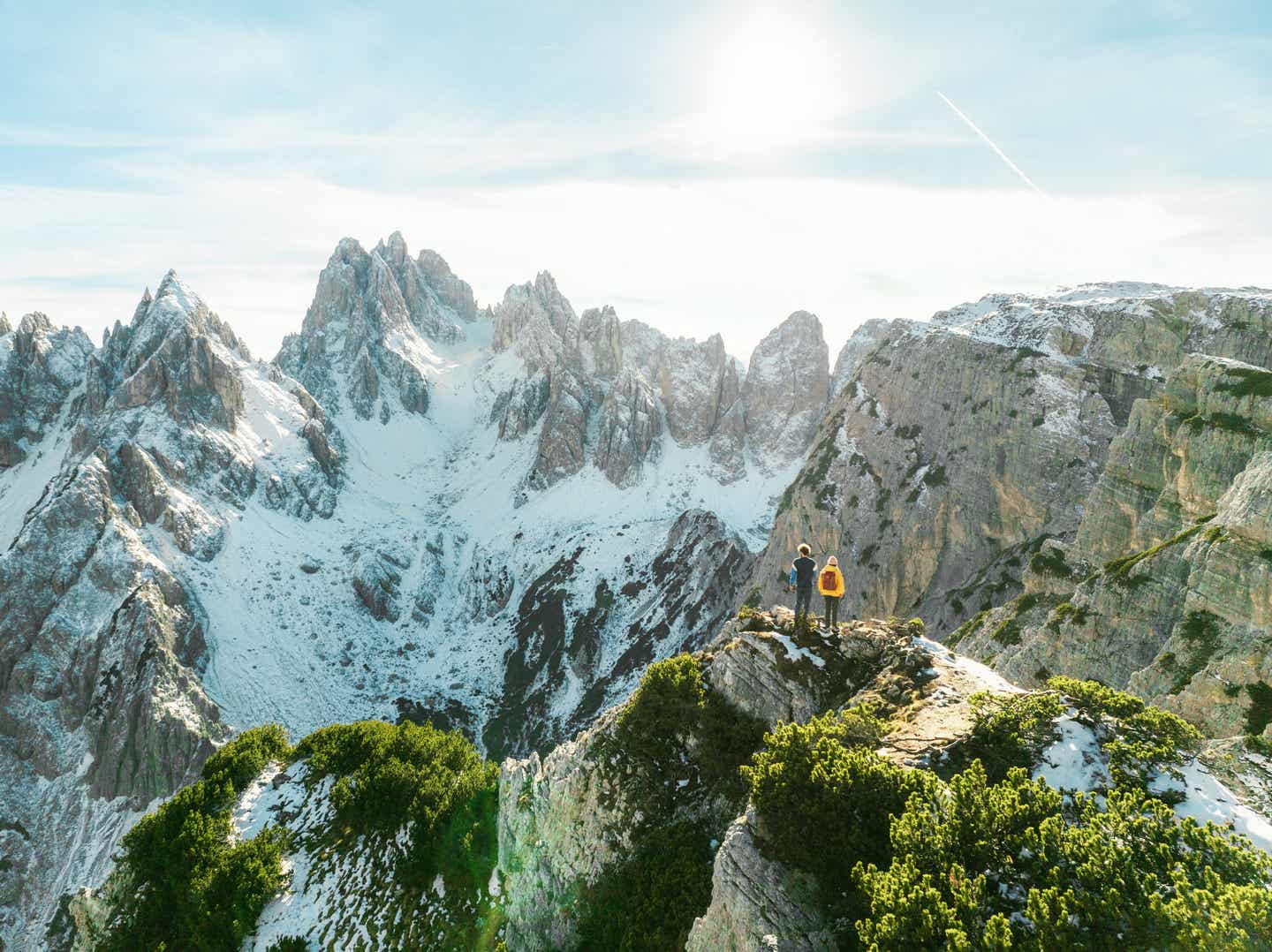 Südtirol Urlaub mit DERTOUR. Junges Paar betrachtet das Panorama der Dolomiten von einem Berggipfel aus