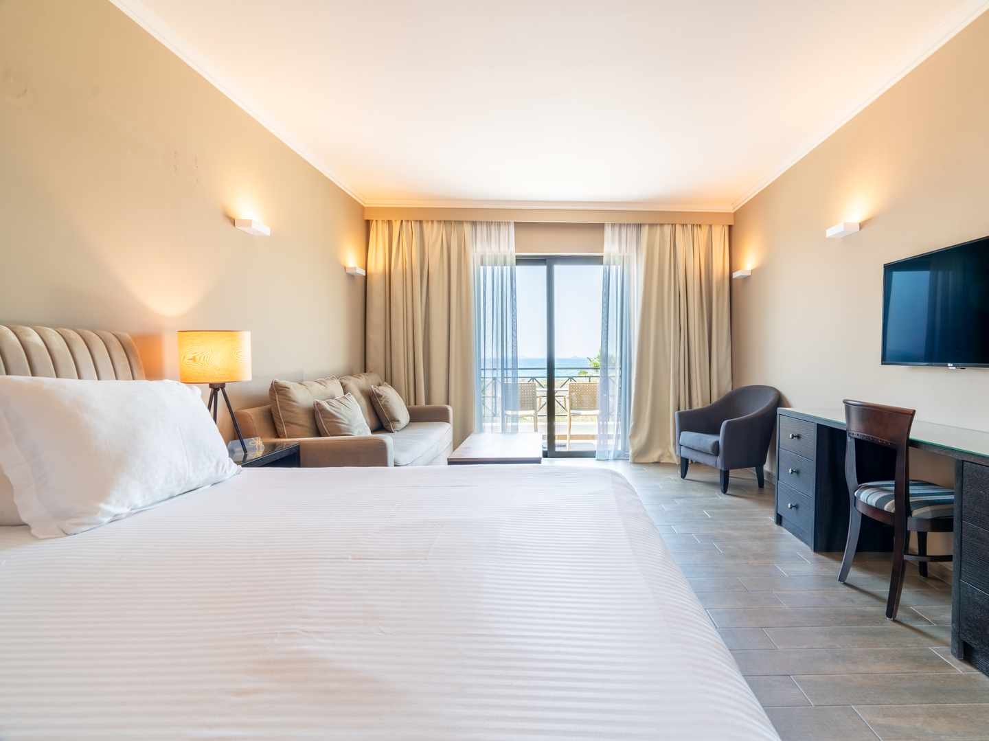 Doppelzimmer im Sentido Pelagos Suites & Spa auf Kos mit großem Bett, Sitzbereich, Schreibtisch, TV und Balkon mit Meerblick