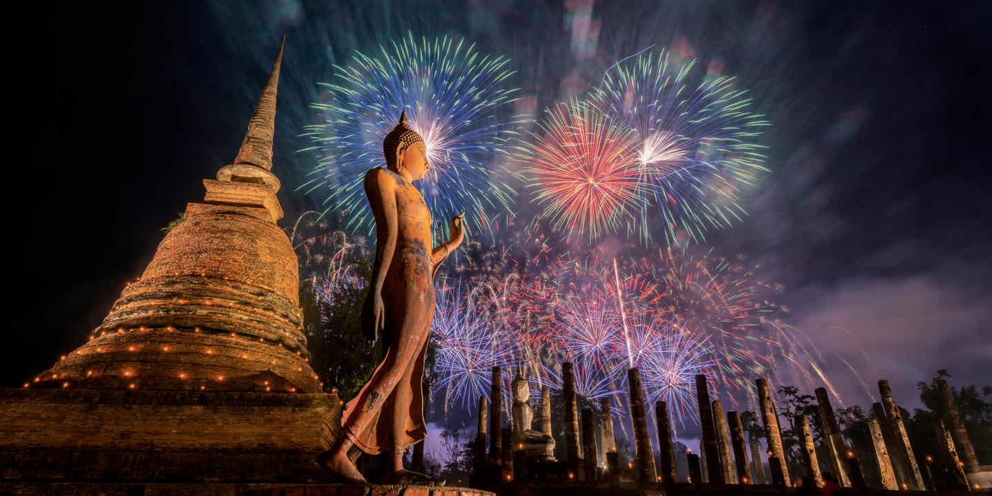 Buntes Feuerwerk in Sukhathai am Loykrathong-Fest; im Vordergrund ein Tempel und eine Statue