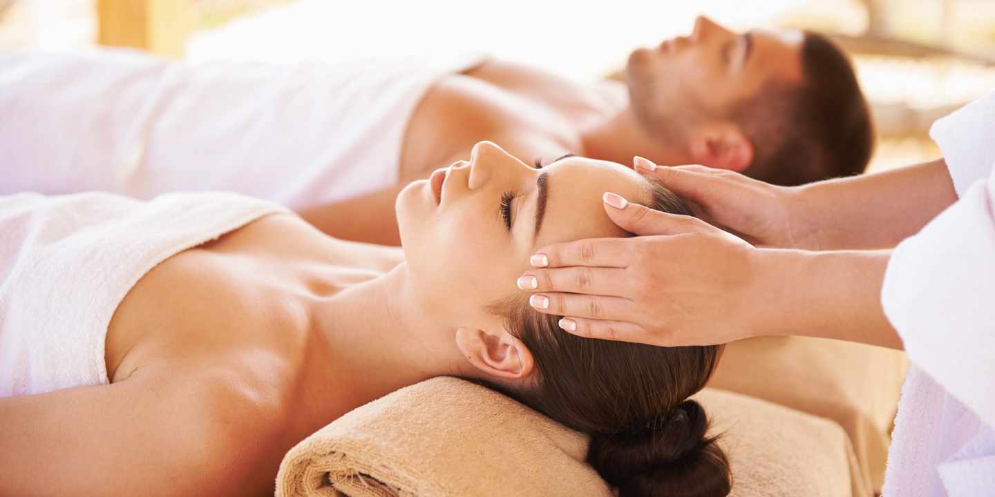 Ein Paar genießt während eines Wellnessurlaubs eine entspannende Kopfmassage im Spa-Bereich