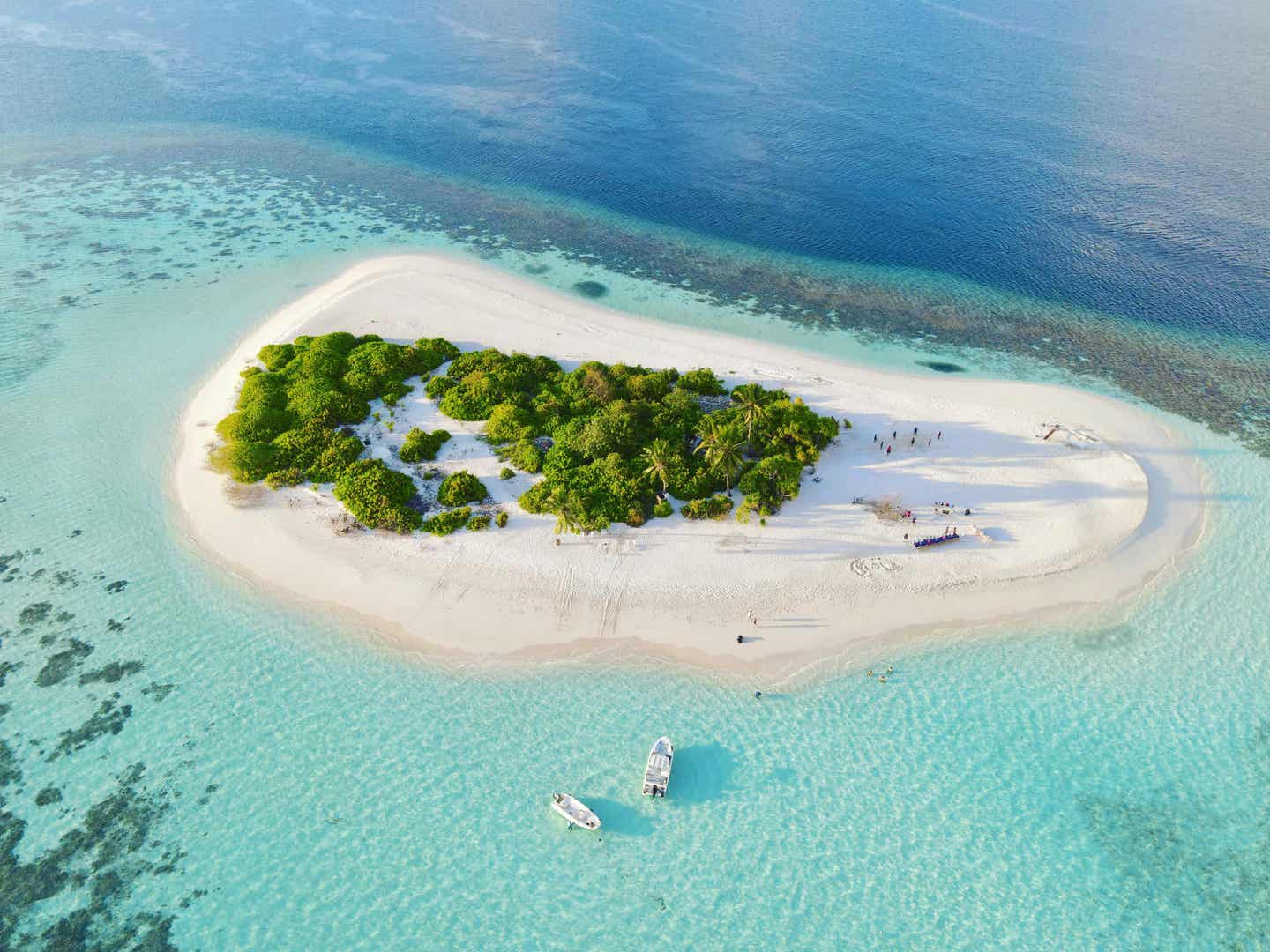 Unbewohnte Insel auf den Malediven, umgeben von türkisblauem Wasser und einem vorgelagerten Korallenriff 