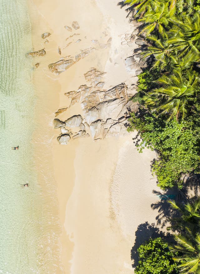 Thailand Urlaub Vogelsperspektive von Strand mit Dschungel, Sand und türkisblauem Meer mit einem landestypischen Boot