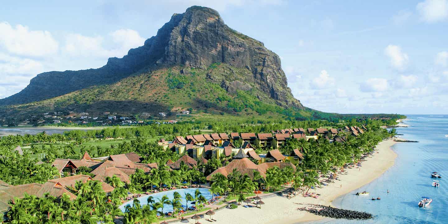 Blick auf den Strand mit Berg im Hintergrund, Paradis Beachcomber Resort in grüner Natur