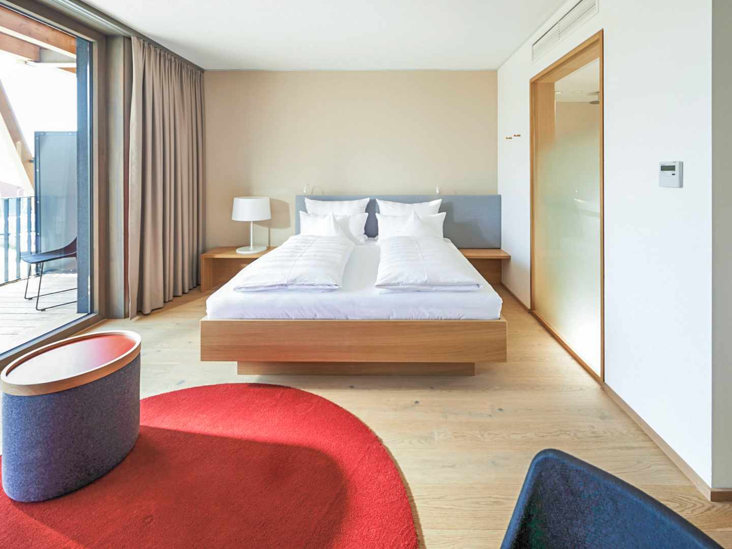 Offene Raumstruktur mit Balkonzugang – kurze Wege zwischen Schlafbereich und Bad erleichtern den Aufenthalt Modernes Doppelzimmer im bora HotSpaResort Radolfzell mit Balkon, Holzboden und klarer Raumgestaltung