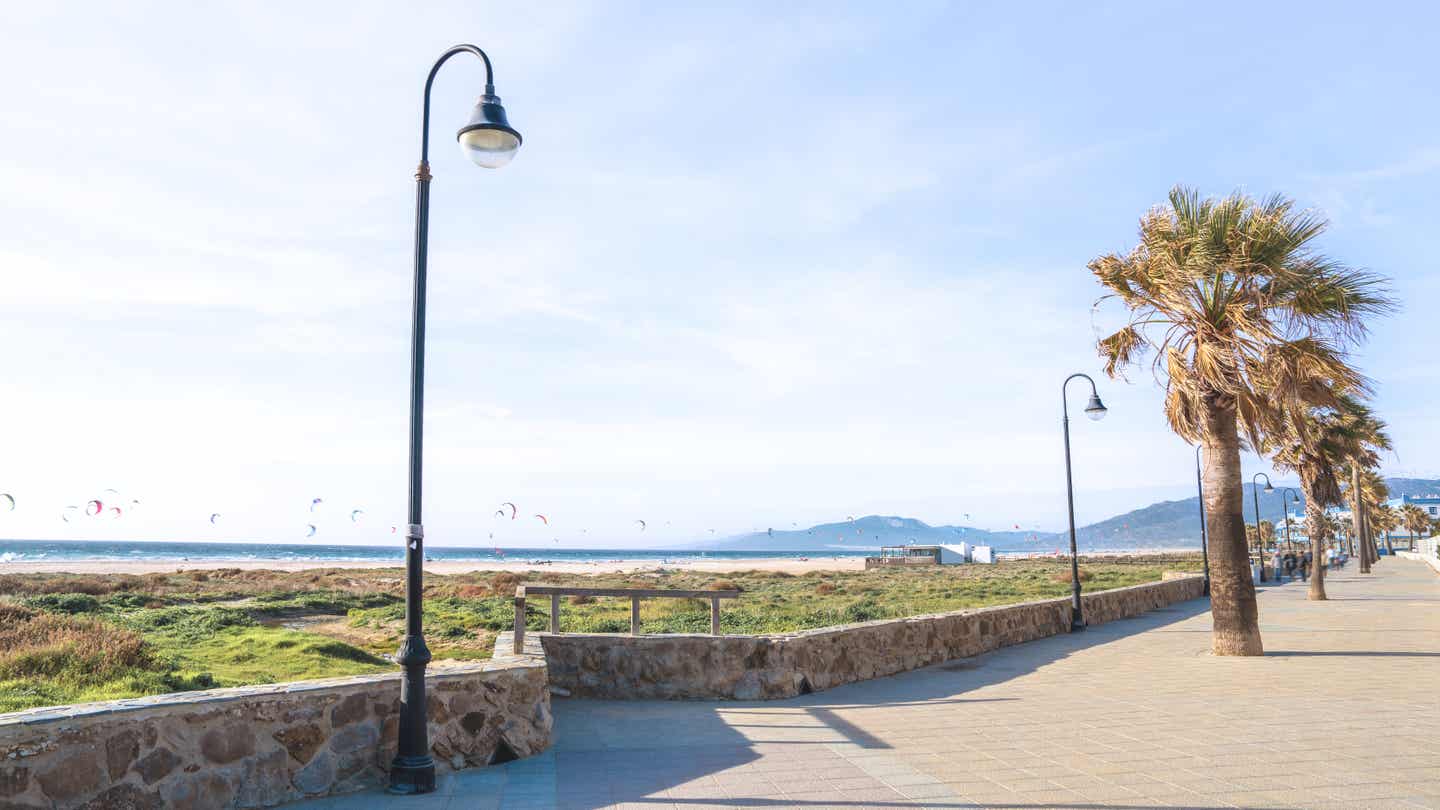Promenade in Tarifa mit Blick aufs Meer – zahlreiche Kites beim Surfen am Himmel über der Küste