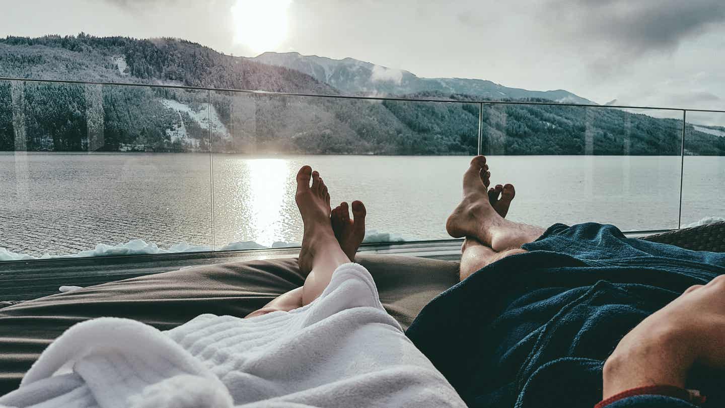 Österreich Urlaub mit DERTOUR. Paar auf Liegen in einem Badehaus am Millstätter See in Kärnten