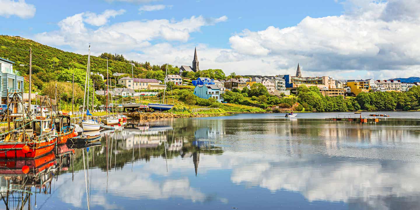 Hafen von Clifden mit Booten und Spiegelungen im Wasser, sonniger Frühlingstag an der Westküste Irlands 
