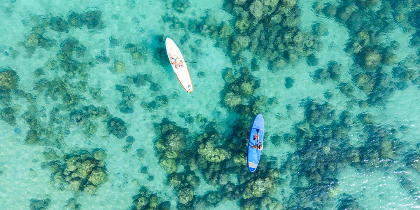 Wasser-Action im Thailand Urlaub: Vogelperspektive von 2 Personen auf SUPs über klarem, türkisfarbenen Wasser