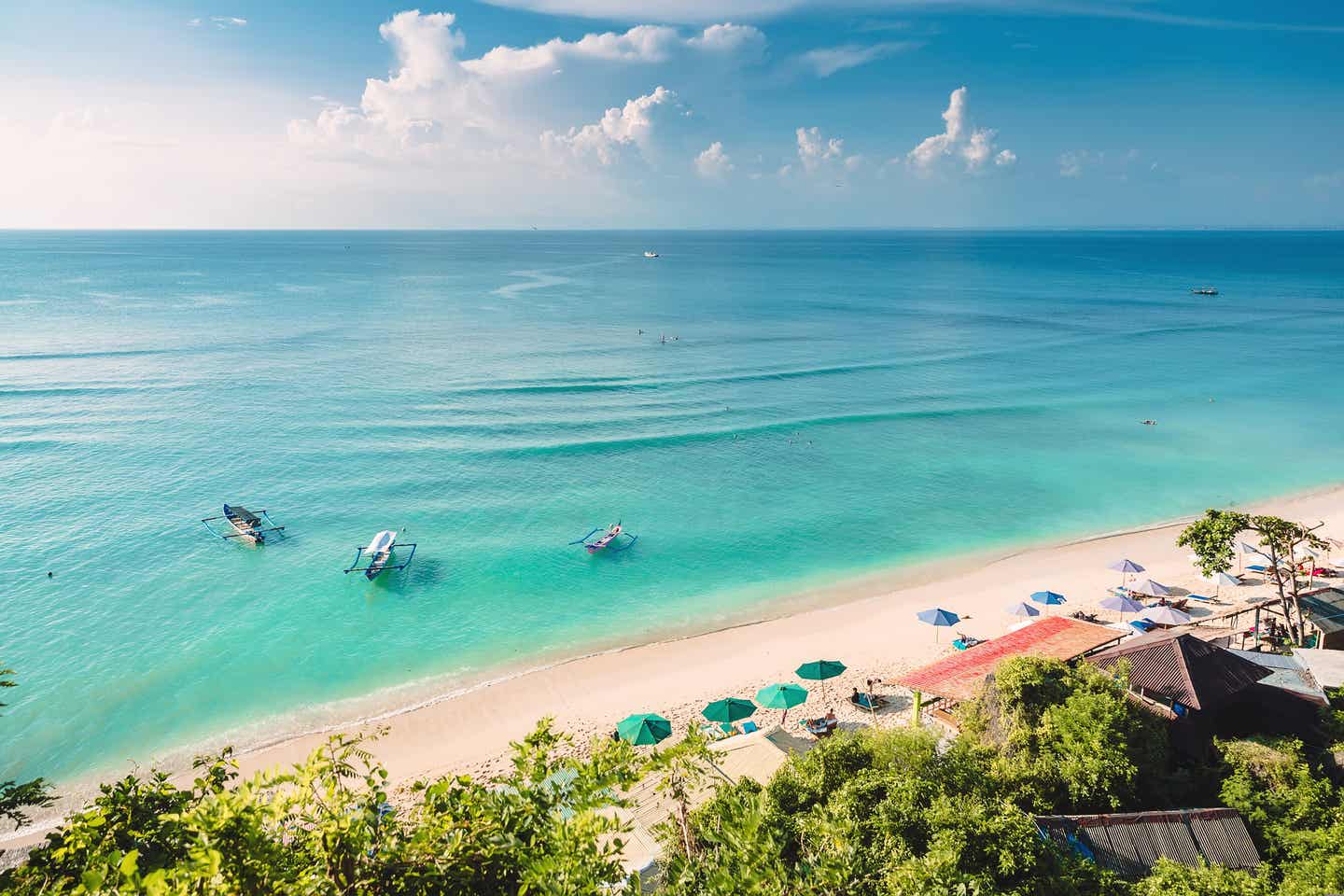 Strand auf Bali mit blaugrünem Wasser und Booten