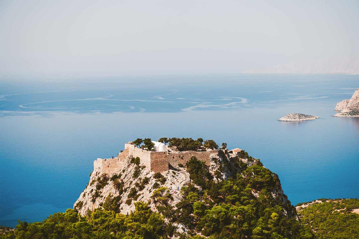 Monolithos Burg auf bewaldetem Felsen vor dem blauen Meer auf Rhodos