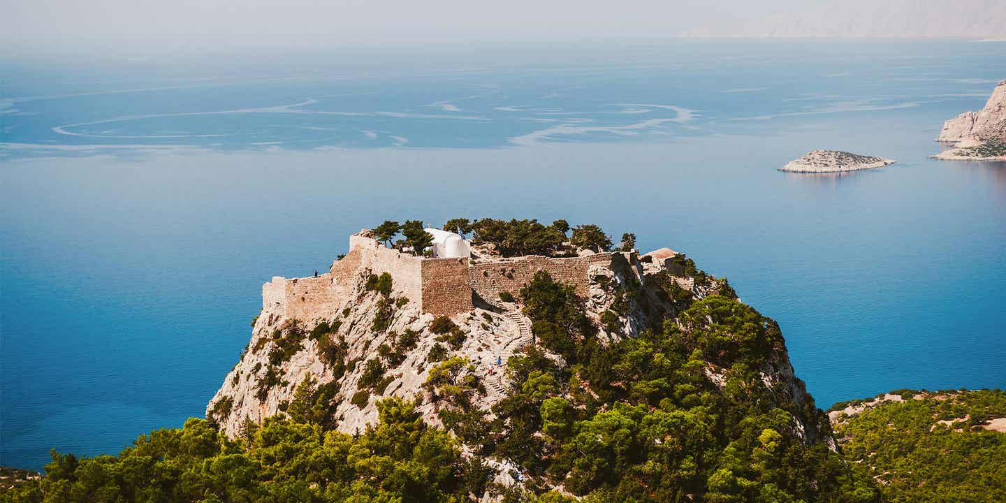 Monolithos Burg auf bewaldetem Felsen vor dem blauen Meer auf Rhodos