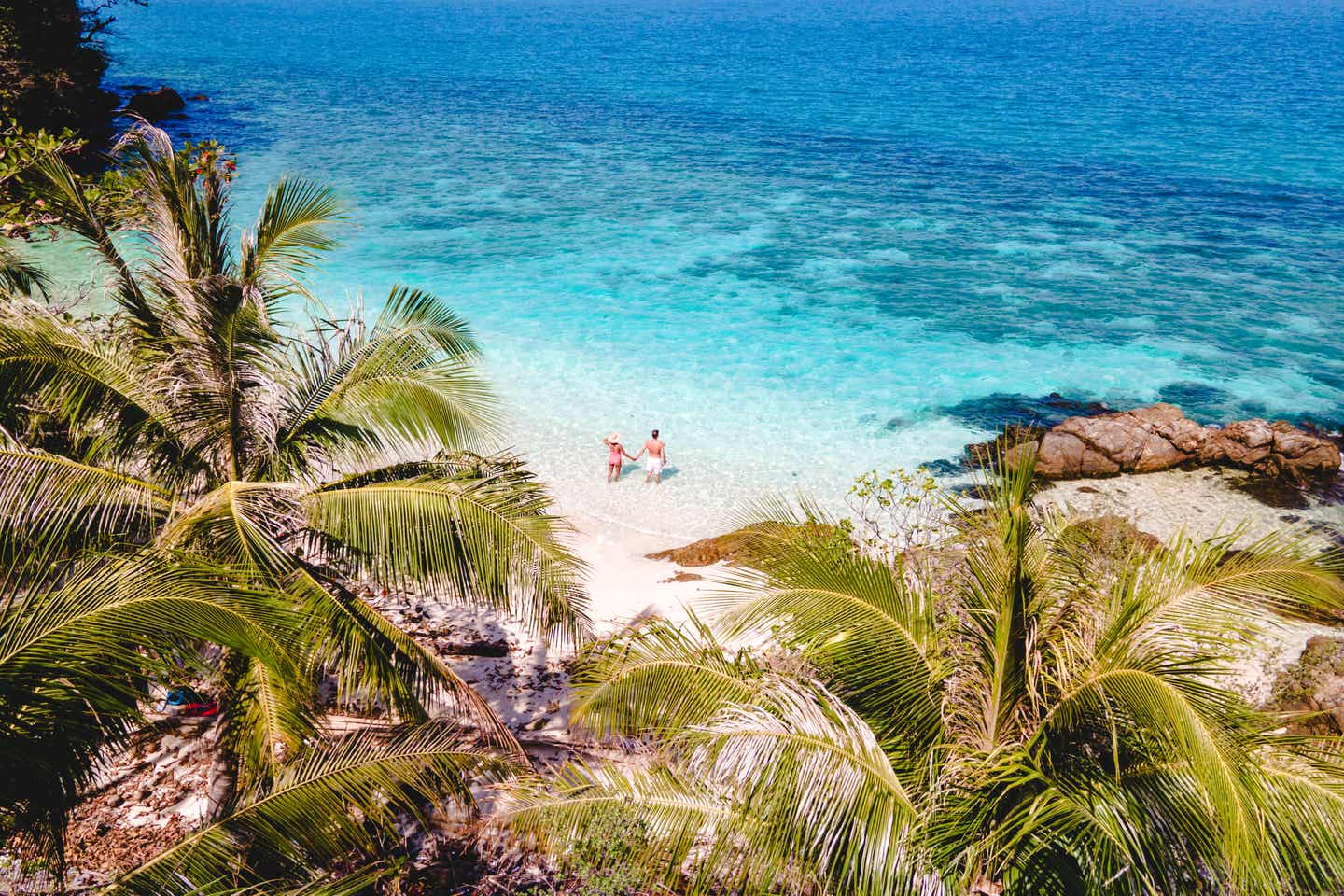 Ein Paar genießt den ruhigen Strand auf Koh Wai Island in Thailand – türkisfarbenes Meer, weiße Sandküste und Palmen