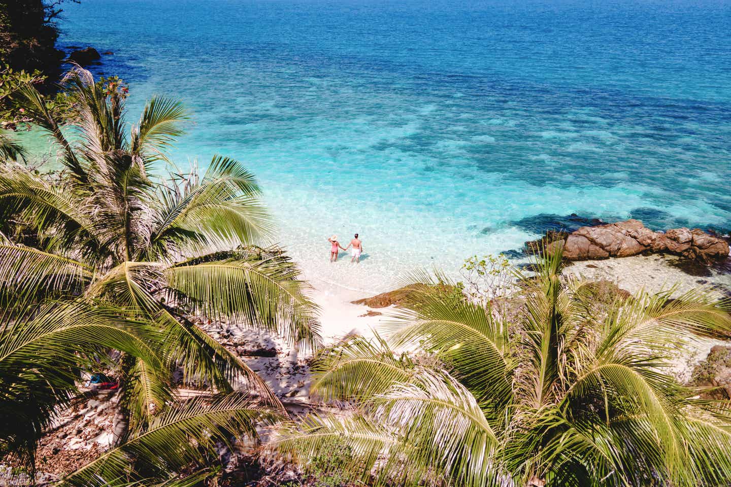 Ein Paar genießt den ruhigen Strand auf Koh Wai Island in Thailand – türkisfarbenes Meer, weiße Sandküste und Palmen