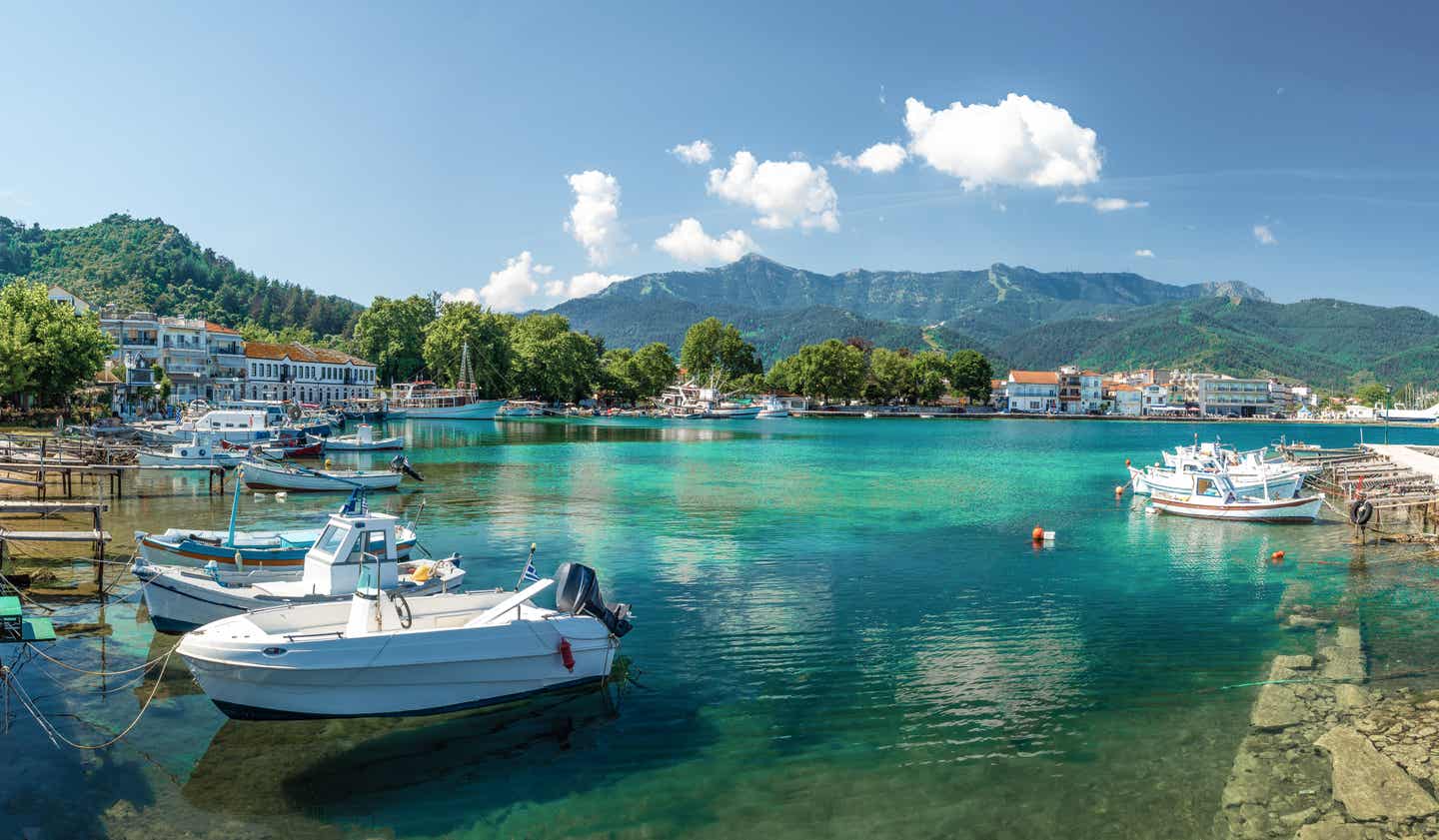 Kleine Fischerboote in der idyllischen Hafenstadt Limenas auf Thassos mit imposanten Bergen im Hintergrund