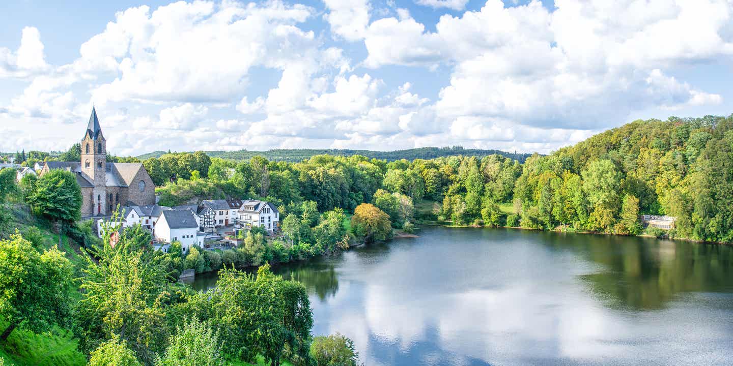 Blick auf das Almener Maar, das von dichten Wäldern umgeben ist 