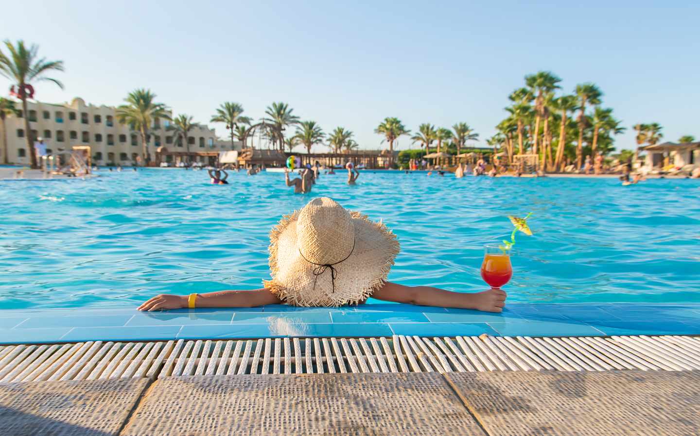 Herbstferien-Urlaub mit Kindern: Mädchen mit Strohhut entspannt am Pool eines Familienresorts in Dubai