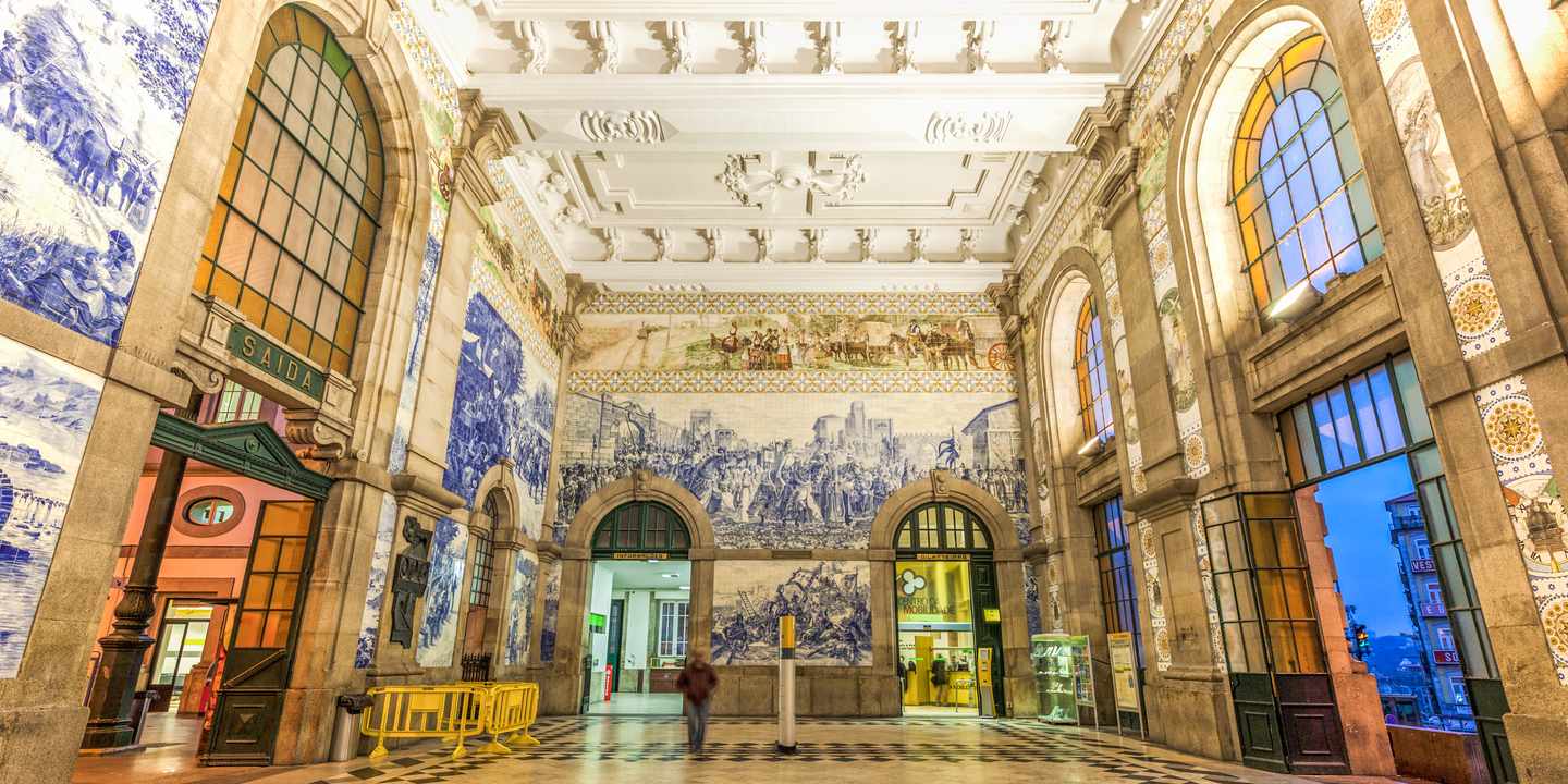 Sehenswürdigkeiten in Porto – Innenhalle des Bahnhofs São Bento in Porto mit Azulejo-Fliesen und hohen Rundbogenfenstern