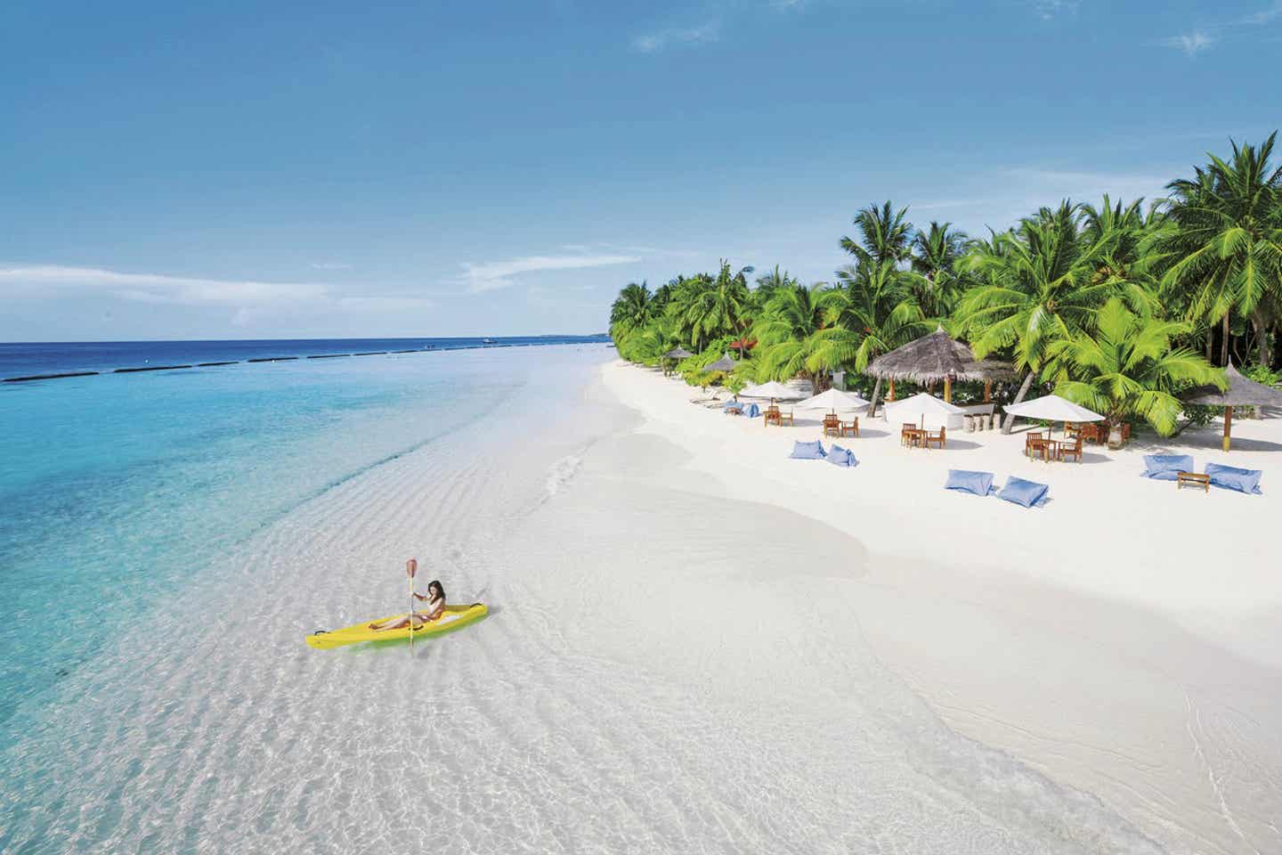 Eine Kanufahrerin im seichten Wasser des Kurumba Maldives Strandes