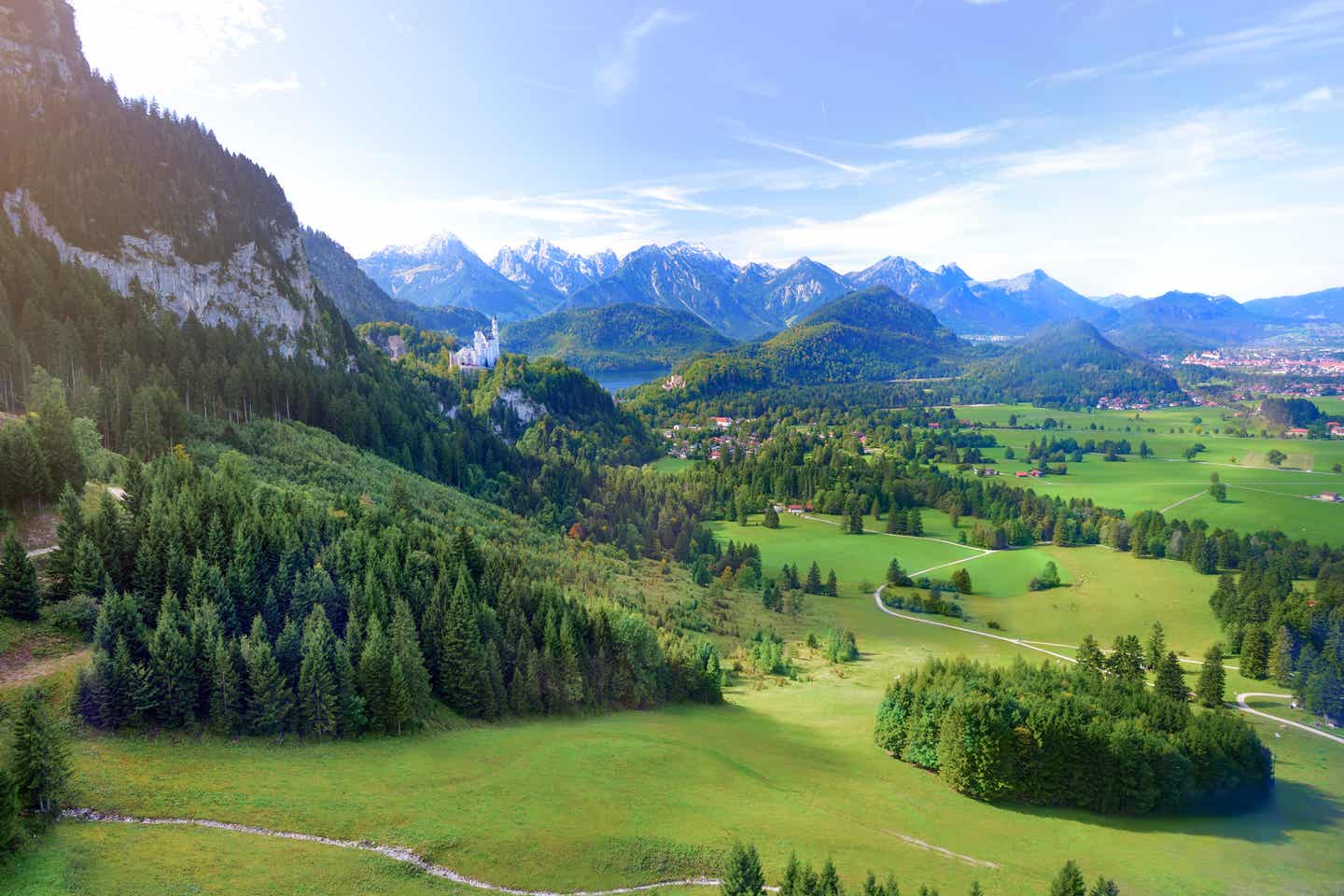 Ein Must-see im Urlaub in Bayern ist das Schloss Neuschwanstein, das umgeben von grünen Hügeln und majestätischen Bergen ist