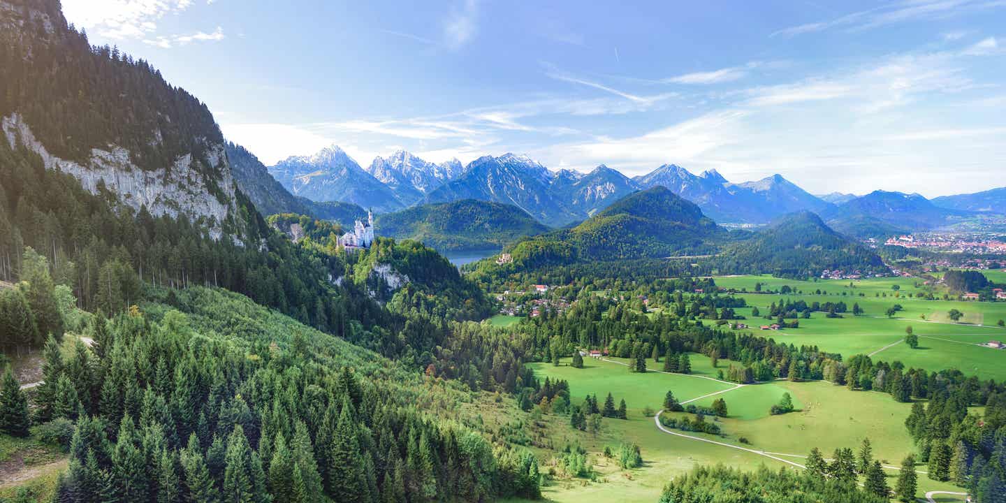 Ein Must-see im Urlaub in Bayern ist das Schloss Neuschwanstein, das umgeben von grünen Hügeln und majestätischen Bergen ist