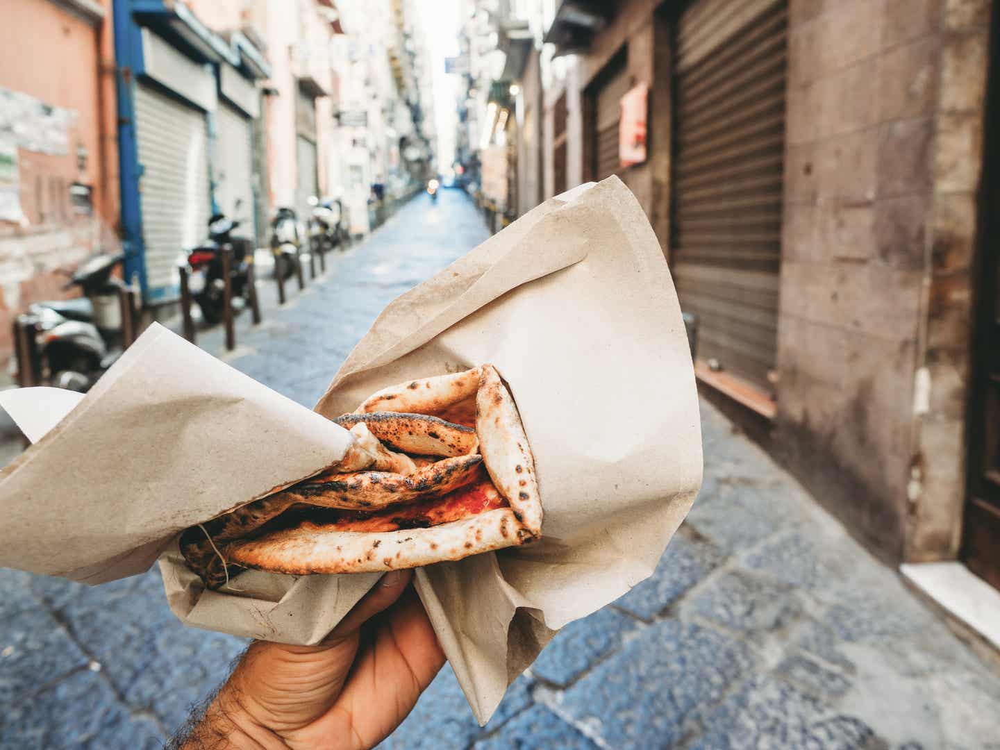 Städtereise Neapel: Blick eines Mannes auf Pizza a portafoglio