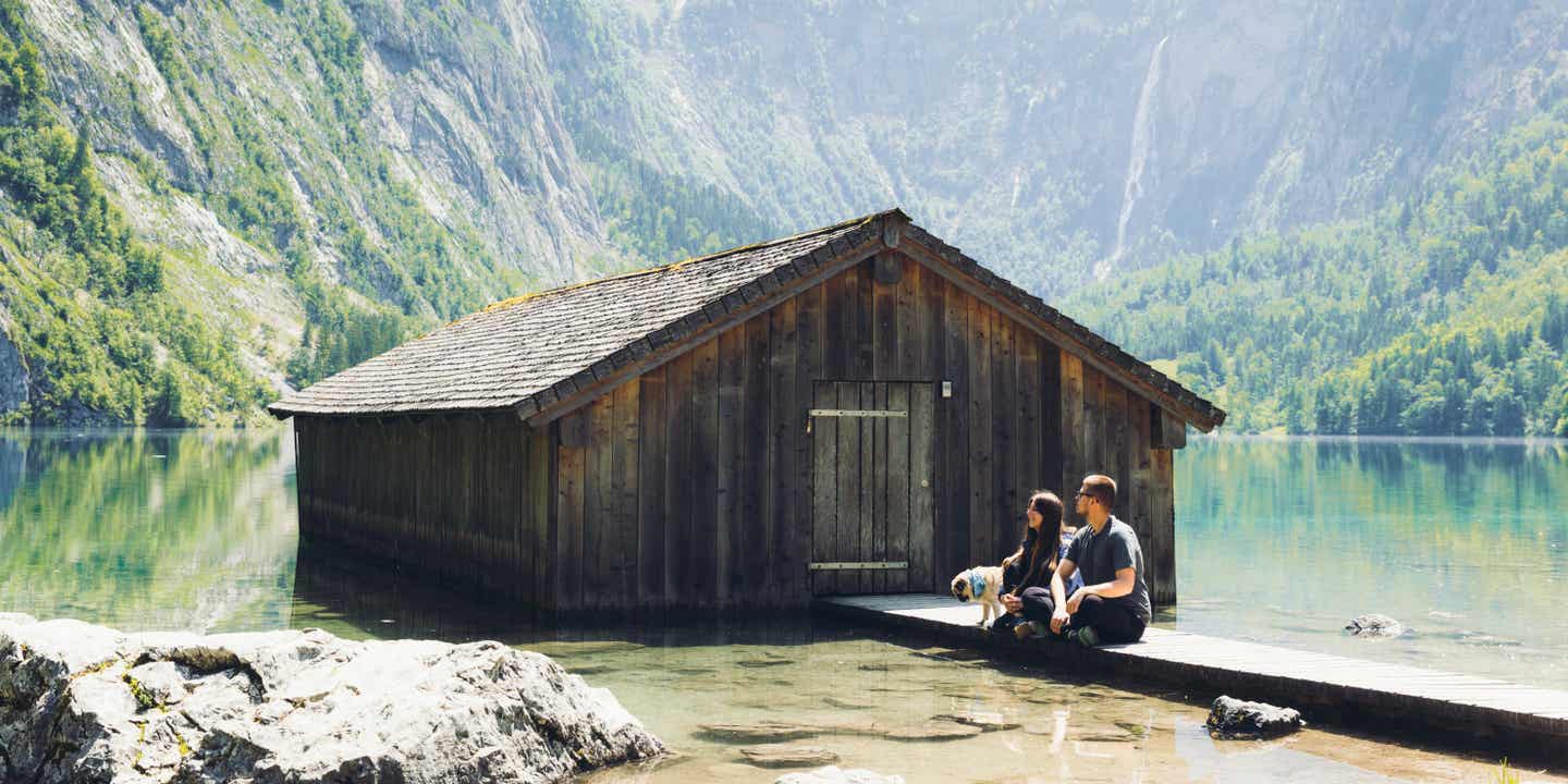 Ein Pärchen sitzt an einem Holzhaus am See in den bayerischen Alpen