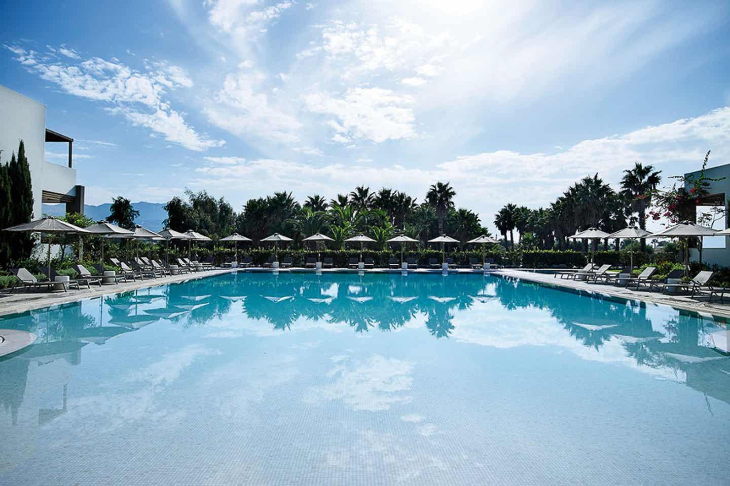 Sentido Pelagos Suites & Spa Pool mit Palmen und Sonnenliegen