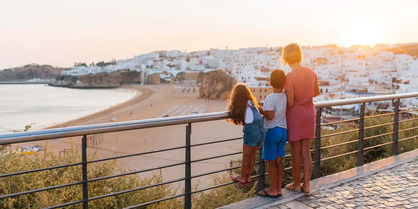 Familie blickt von Aussichtspunkt auf Strand und Stadt Albufeira an der Algarve in Portugal