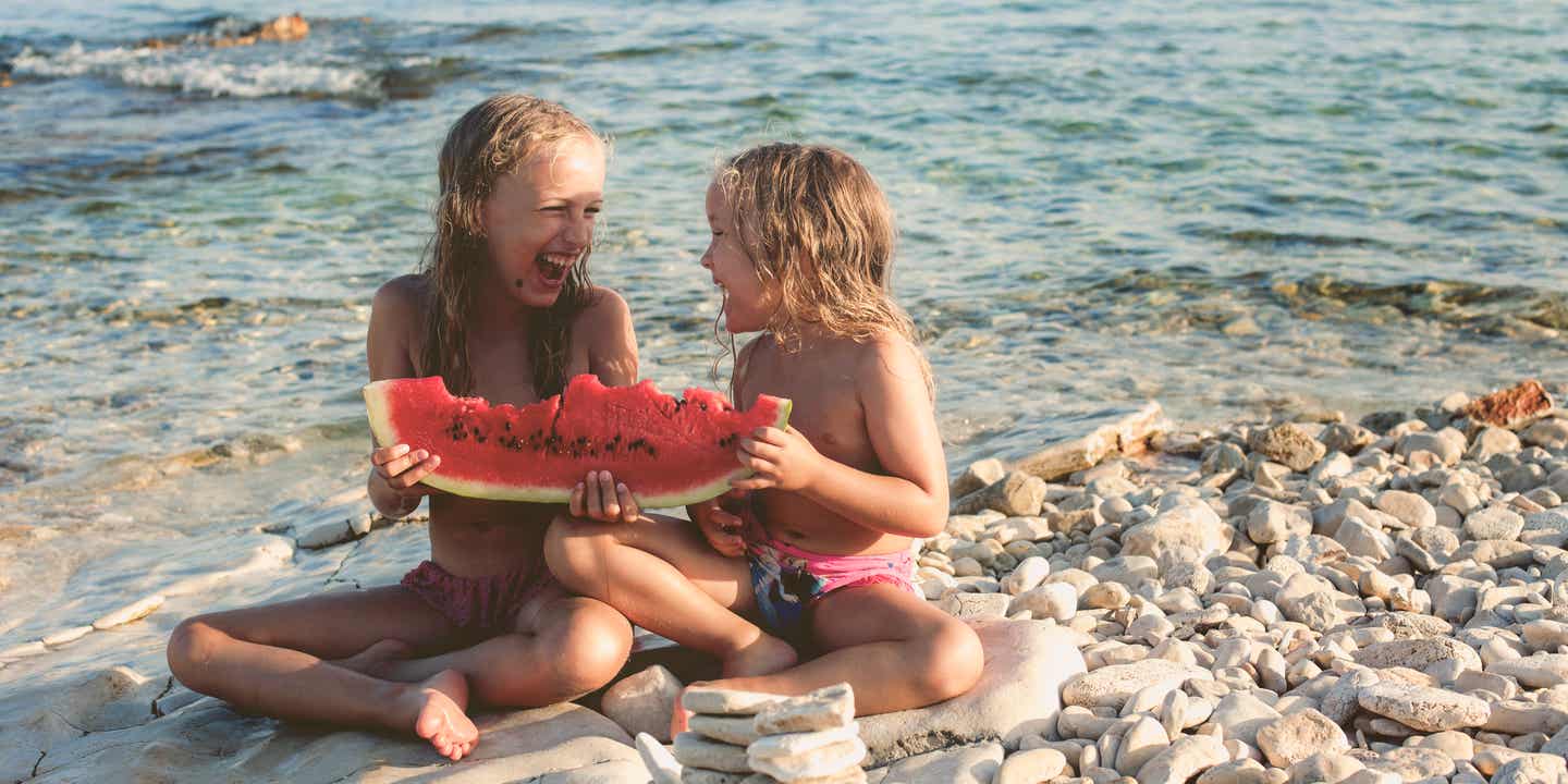 Kroatien mit Kindern: zwei Mädchen essen eine Wassermelone am Strand