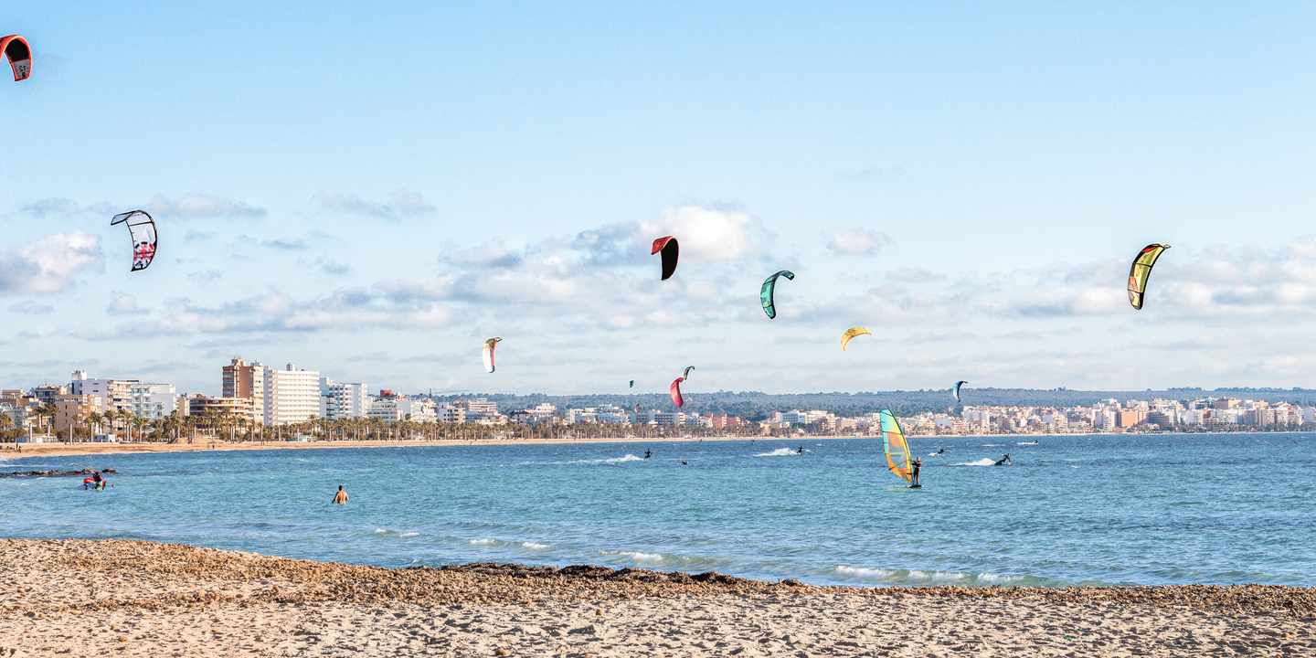 Kitesurfer vor der Küste von Can Pastilla mit Blick auf Strand und Hotelreihe entlang der Bucht Mallorcas