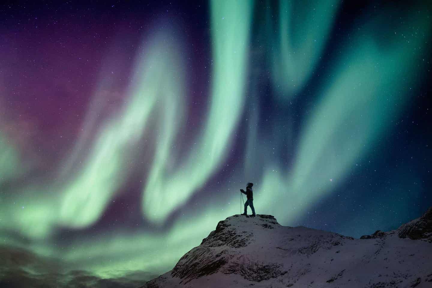 Polarlichter sehen. Mann steht vor Polarlichtern.