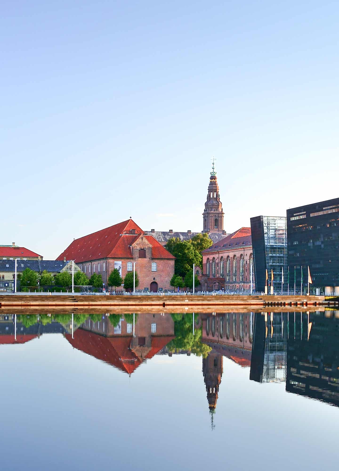Königliche Bibliothek „der Schwarze Diamant": deine Städtereise mit unseren Geheimtipps bietet einen Mix aus alt und neu Blick von Wasser auf eine Bibliothek die die Form eines schwarzen Diamanten hat
