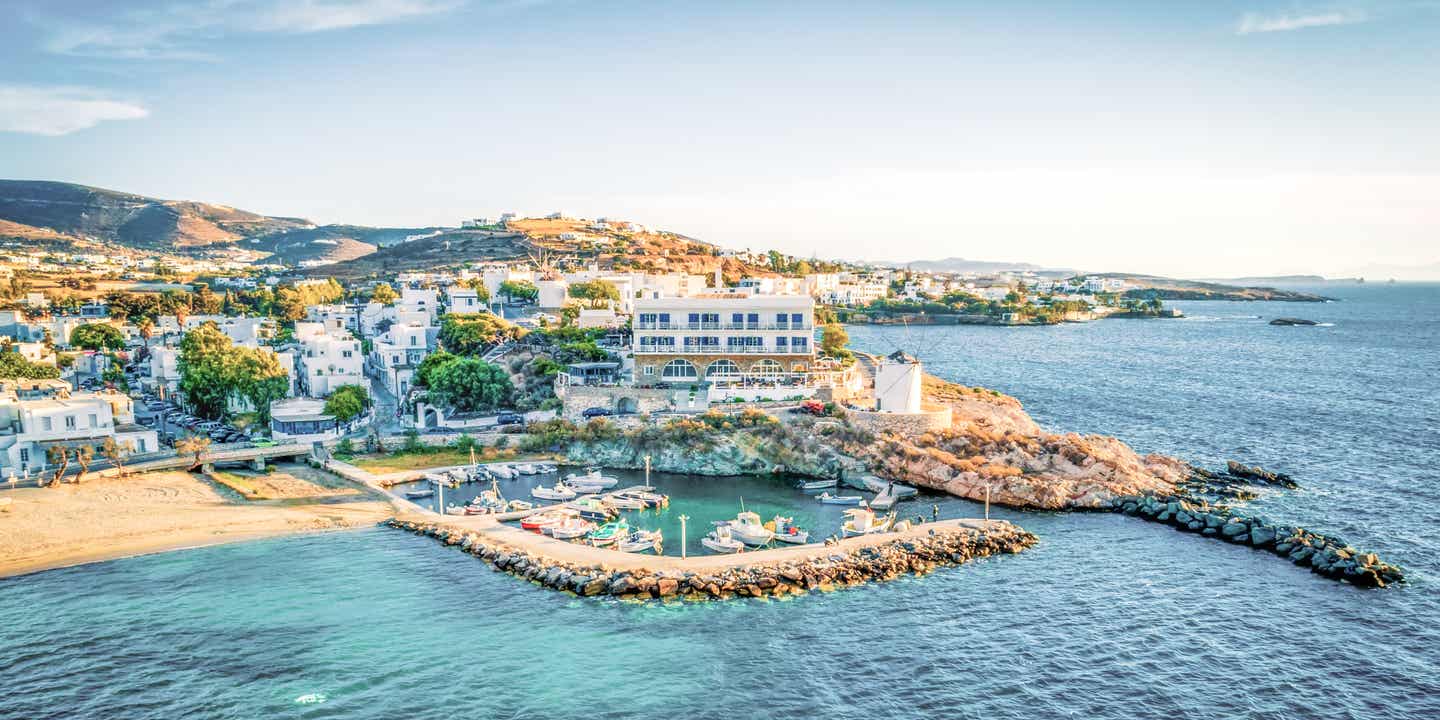 Blick auf den Hafen von Paros in der Ägäis mit blauem Wasser und Bergen auf der Insel im Hintergrund