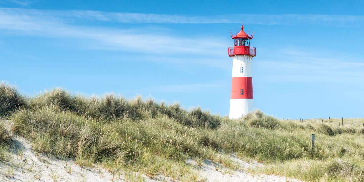  Rot-weißer Leuchtturm auf Sylt zwischen Dünenlandschaft und Strandhafer unter blauem Himmel