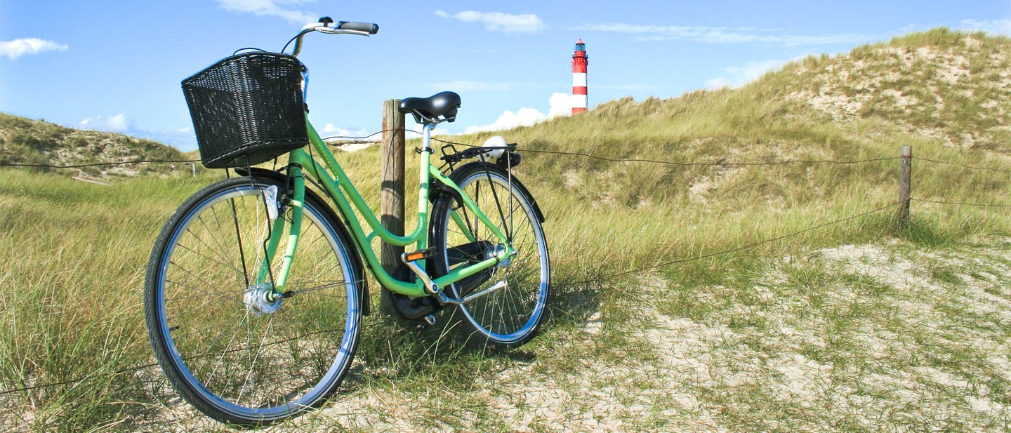 Fahrradtouren in Norddeutschland: Ein hellgrünes Fahrrad lehnt an einem Zaun auf einer Düne