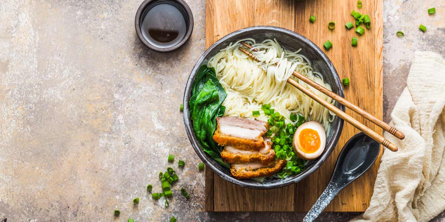 Eine dampfende Ramen-Suppe mit Ei, Schweinefleisch, Frühlingszwiebeln und Bok choy in einem Restaurant in Tokio