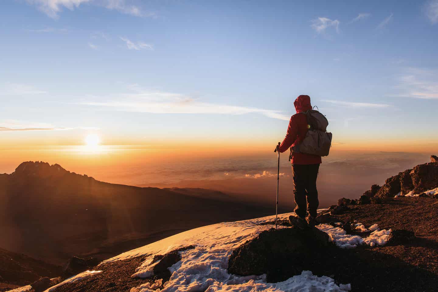 Wanderer beobachtet Sonnenaufgang von der Spitze des Kilimandscharos